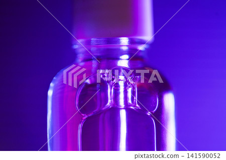 Close-up of a clear glass bottle with a white cap, illuminated by purple lighting, showcasing the bottle's shape and reflections against a gradient background 141590052