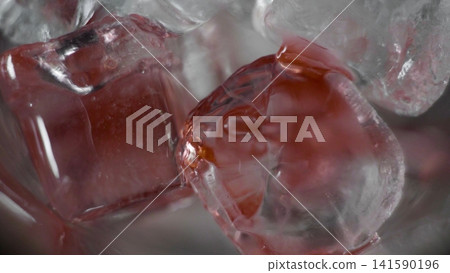 Ice cubes with hints of red liquid, creating a refreshing and cold sensation. Close-up texture abstract background Ice cubes with hints of red liquid, creating a refreshing and cold sensation. Close-up texture abstract background 141590196