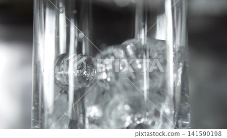Ice cubes filling a clear glass with refreshing water, creating a cool and hydrating beverage Ice cubes filling a clear glass with refreshing water, creating a cool and hydrating beverage 141590198