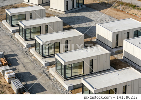 Modern modular housing units under construction on a gravel lot Modern modular housing units under construction on a gravel lot 141590212