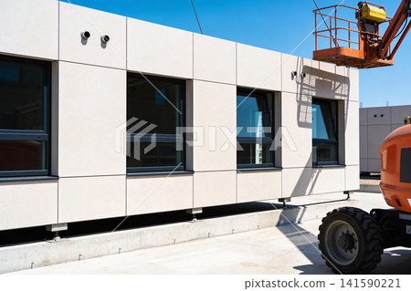 Modern building facade construction with windows and aerial lift equipment Modern building facade construction with windows and aerial lift equipment 141590221