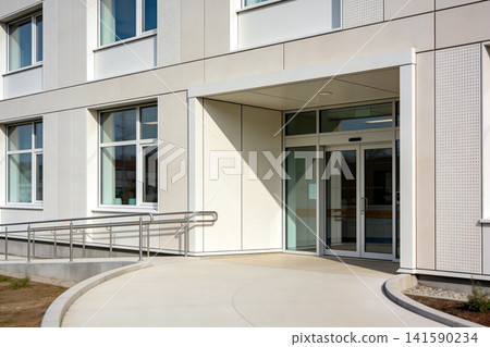 Modern building entrance with automatic glass doors and accessible ramp Modern building entrance with automatic glass doors and accessible ramp 141590234