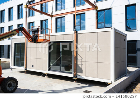 Modular building unit being lifted into place by crane and boom lift Modular building unit being lifted into place by crane and boom lift 141590257