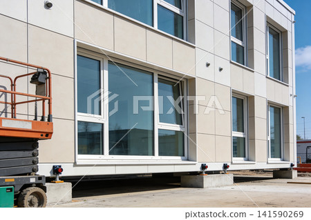 Modern building facade with large windows and a scissor lift at construction site Modern building facade with large windows and a scissor lift at construction site 141590269