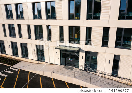Modern office building facade with large windows and accessible entrance ramp Modern office building facade with large windows and accessible entrance ramp 141590277