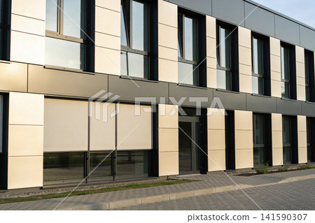 Modern office building facade with large windows and beige paneling Modern office building facade with large windows and beige paneling 141590307