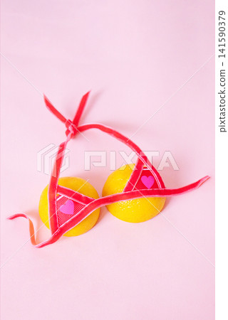 Two yellow lemons adorned with red ribbon and heart-shaped decorations on a soft pink background, creating a playful and whimsical visual composition Two yellow lemons adorned with red ribbon and heart-shaped decorations on a soft pink background, creating a playful and whimsical visual composition 141590379