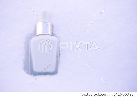Clear glass dropper bottle with silver cap resting in fresh white snow, showcasing a minimalist design against a winter landscape background Clear glass dropper bottle with silver cap resting in fresh white snow, showcasing a minimalist design against a winter landscape background 141590382