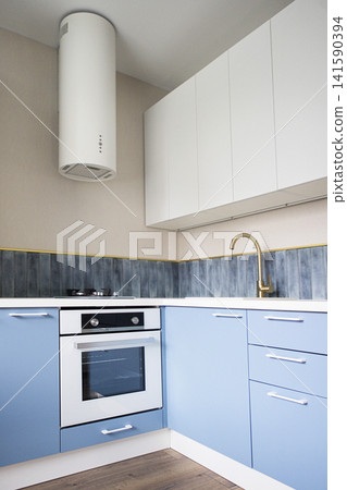 Modern kitchen interior featuring blue cabinetry, white oven, and gold faucet with a sleek design, showcasing a contemporary aesthetic in a well-lit space Modern kitchen interior featuring blue cabinetry, white oven, and gold faucet with a sleek design, showcasing a contemporary aesthetic in a well-lit space 141590394