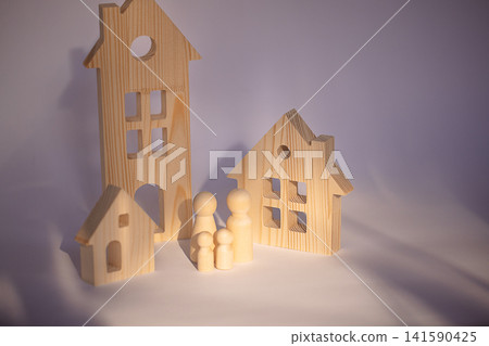 Wooden toy houses and figurines arranged on a light background, showcasing various shapes and sizes of houses and family figures in a playful setting Wooden toy houses and figurines arranged on a light background, showcasing various shapes and sizes of houses and family figures in a playful setting 141590425