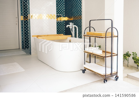 Stylish mobile shelf with clean towels in the bathroom. The modern room is decorated with blue and white tiles in the form of fish scales. Stylish mobile shelf with clean towels in the bathroom. The modern room is decorated with blue and white tiles in the form of fish scales. 141590586