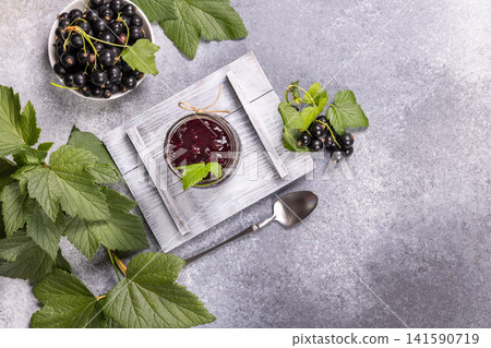 Blackcurrant jam with fresh berries and green leaves 141590719