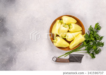 Fresh yellow peppers in wood bowl with cleaver Fresh yellow peppers in wood bowl with cleaver 141590737