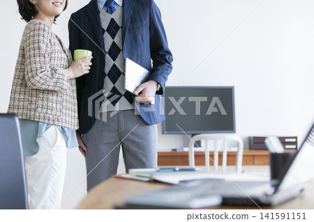 A businessman and a businesswoman chatting while standing. A businessman and a businesswoman chatting while standing. 141591151
