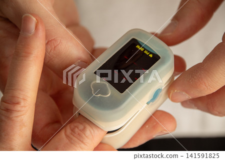 Checking pulse with a small device on a person's finger Checking pulse with a small device on a person's finger 141591825