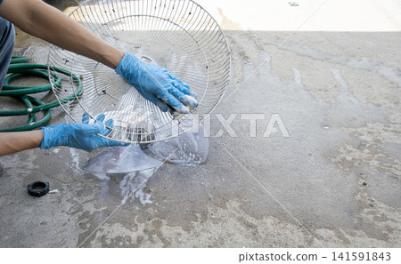 Workers are cleaning the grilles of a fan. Workers are cleaning the grilles of a fan. 141591843