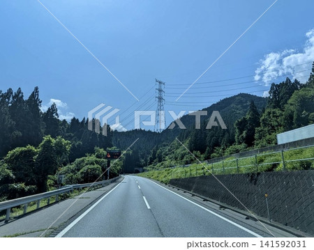 A mountain highway and tunnel entrance; a landscape of blue sky and power transmission towers. A mountain highway and tunnel entrance; a landscape of blue sky and power transmission towers. 141592031