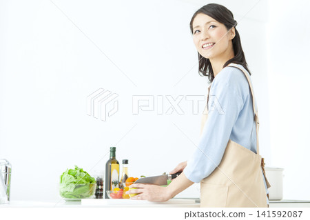 A housewife in an apron cooking A housewife in an apron cooking 141592087