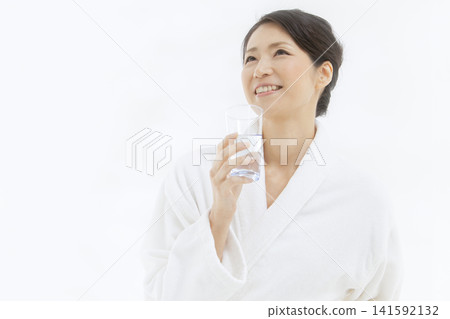 一位中年婦女穿著浴袍喝水。 141592132