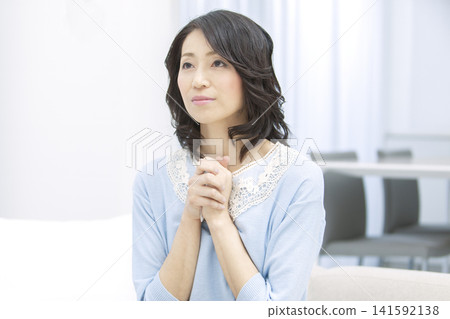一位中年婦女雙手合十祈禱。 141592138