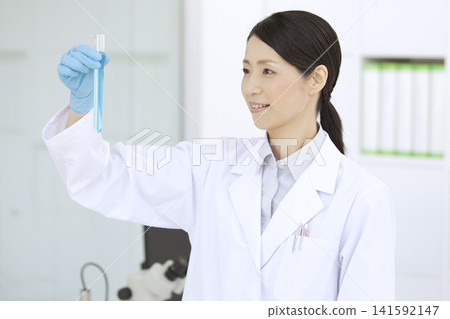A woman in a white coat holding a test tube A woman in a white coat holding a test tube 141592147