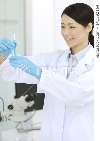一位身穿白大褂的女子手持試管 141592164