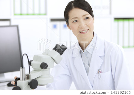 一位身穿白大褂的女士正在透過顯微鏡觀察。 141592165