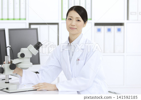 A woman in a white coat looking through a microscope A woman in a white coat looking through a microscope 141592185