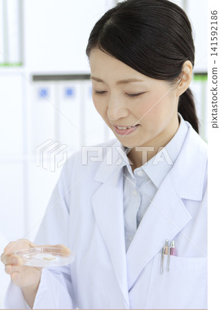 A woman in a white coat performing an examination A woman in a white coat performing an examination 141592186