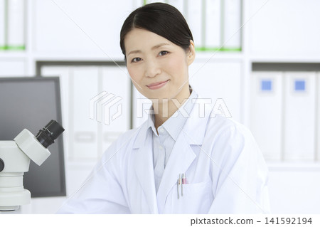 一位身穿白大褂的女士正在透過顯微鏡觀察。 141592194