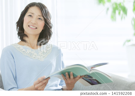 一位中年婦女在客廳看書。 141592208