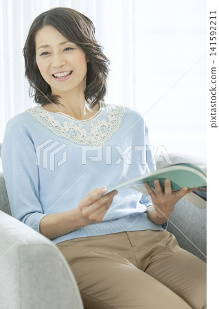 一位中年婦女在客廳看書。 141592211