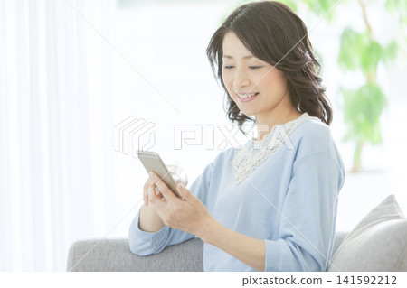 一位中年婦女正在看她的智慧型手機。 141592212
