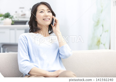 A middle-aged woman making a phone call on her smartphone. 141592240