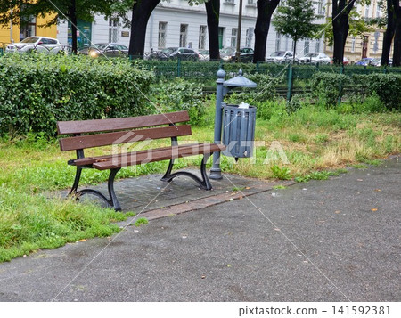 Empty Wooden Park Bench Beside Public Trash Bin After Rain 141592381