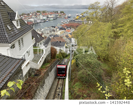 A red cable car ascending the mountains of Bergen, Norway, and the scenery of the harbor town. A red cable car ascending the mountains of Bergen, Norway, and the scenery of the harbor town. 141592448