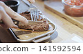 Hands cutting grilled steak on wooden board 141592594