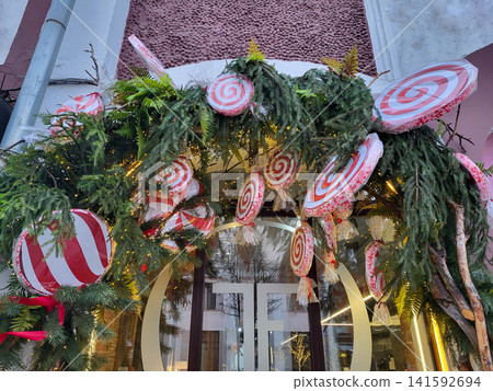 A garland of Christmas tree branches with Christmas toys and candies hangs above the entrance. The concept of Christmas and New Year A garland of Christmas tree branches with Christmas toys and candies hangs above the entrance. The concept of Christmas and New Year 141592694