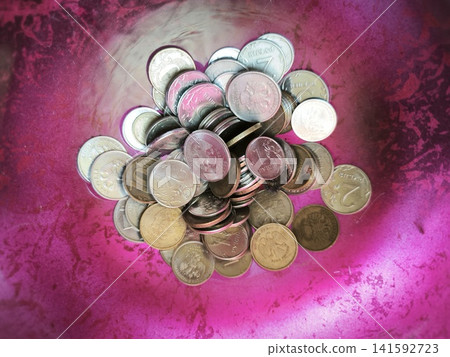 A pile of coins against a bright pink-and-purple background 141592723
