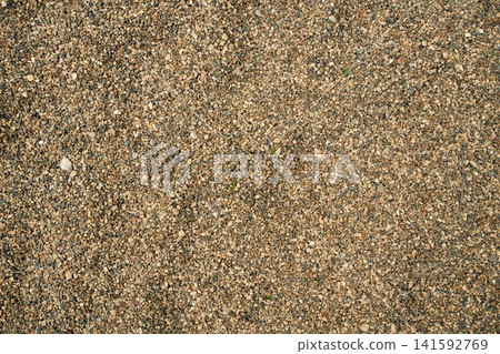 Brown quarry sand layer close-up with uneven mineral grain density, highlighting earthy tones and rough 141592769