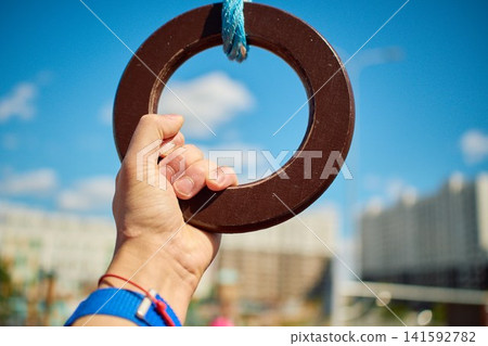 Hand holding wooden gymnastics ring close up Hand holding wooden gymnastics ring close up 141592782