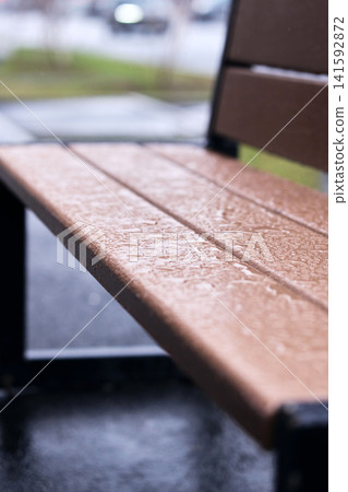 Rain beads on a lacquered wooden bench, illustrating durable outdoor furniture protection 141592872
