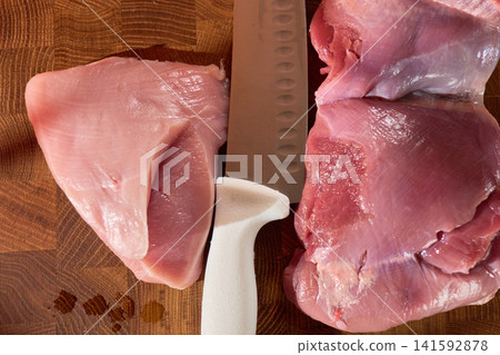 Moody raw meat on wooden cutting board with white knife handle, low warm lighting creates dramatic shadows and glossy fat highlights, intimate late night kitchen prep Moody raw meat on wooden cutting board with white knife handle, low warm lighting creates dramatic shadows and glossy fat highlights, intimate late night kitchen prep 141592878