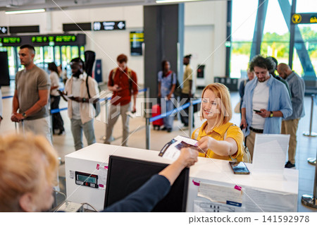 Young woman checking in at airport with passport and boarding pass Young woman checking in at airport with passport and boarding pass 141592978