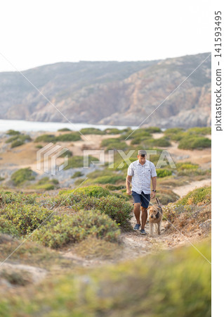 Man and airedale terrier walking coastal path enjoying nature Man and airedale terrier walking coastal path enjoying nature 141593495