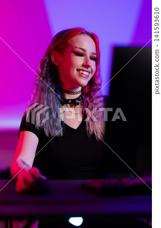 Young woman enjoying gaming in a colorful illuminated room 141593610