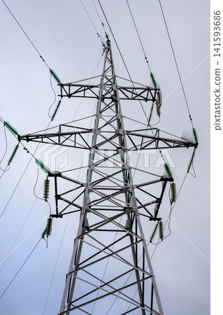 Steel transmission line support structure and high-voltage power line support structure. Network infrastructure with glass insulators distributes electricity, viewed from below. 141593686