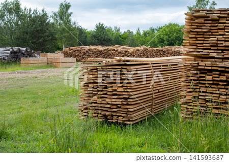 Stacked wooden planks against. Freshly harvested wooden planks for construction Stacked wooden planks against. Freshly harvested wooden planks for construction 141593687