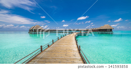Breathtaking wooden jetty stretching over turquoise lagoon toward overwater villas Maldives luxury resort blue sky. Perfect summer vacation travel landscape paradise. Luxury honeymoon getaway scenic Breathtaking wooden jetty stretching over turquoise lagoon toward overwater villas Maldives luxury resort blue sky. Perfect summer vacation travel landscape paradise. Luxury honeymoon getaway scenic 141593858