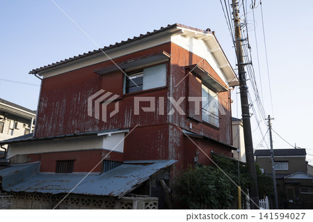 The exterior of this old wooden house, with its reddish-brown facade peeling off, shows signs of weathering and is a retro-style building. The exterior of this old wooden house, with its reddish-brown facade peeling off, shows signs of weathering and is a retro-style building. 141594027